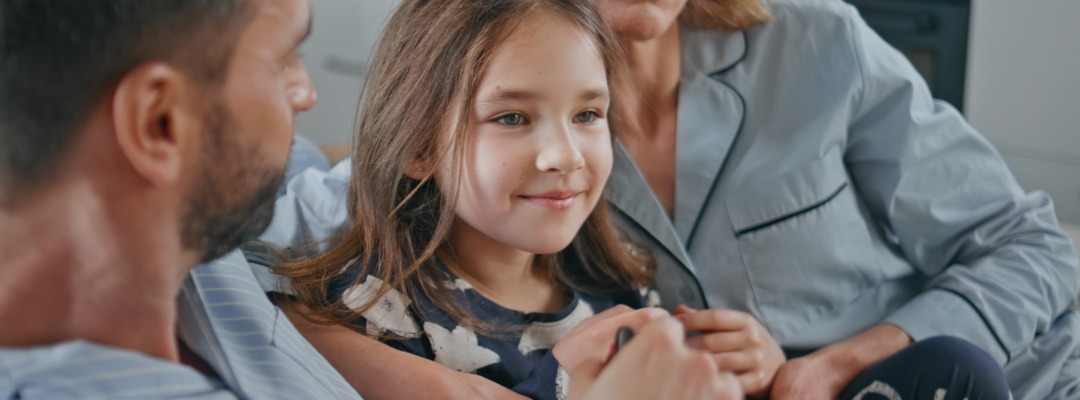 Funny family watching movie at light interior closeup. Child girl eating popcorn Funny family watching movie having fun at light interior closeup. Laughing child girl eating popcorn taking remote controller from father hands. Carefree father mother and daughter relaxing together